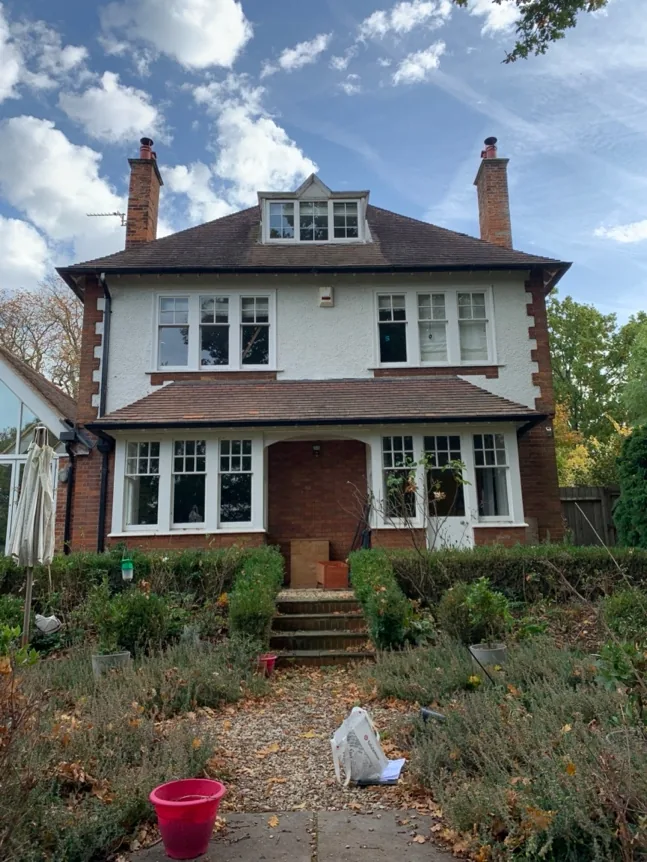 The full front elevation of the 1920s house: red brick, roughcast render and clay-tiled roof