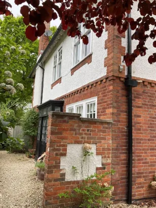 Brick plinth and roughcast render at the corner of the house