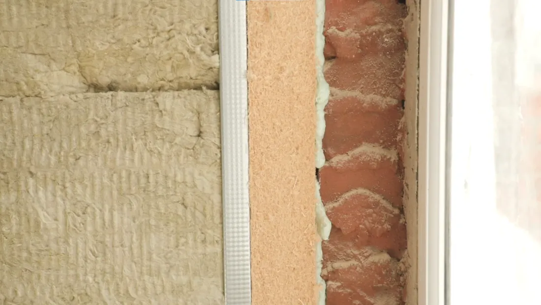 Close-up of the internal wall build-up during the works — insulation layers and wood fibre board meeting the prepared brick at a window reveal