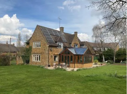 Garden elevation of Orchard House before works, with existing solar array and conservatory