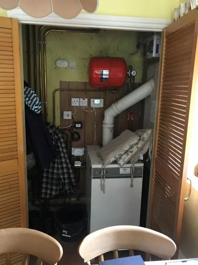 The old oil boiler in its kitchen cupboard with flue and expansion vessel above