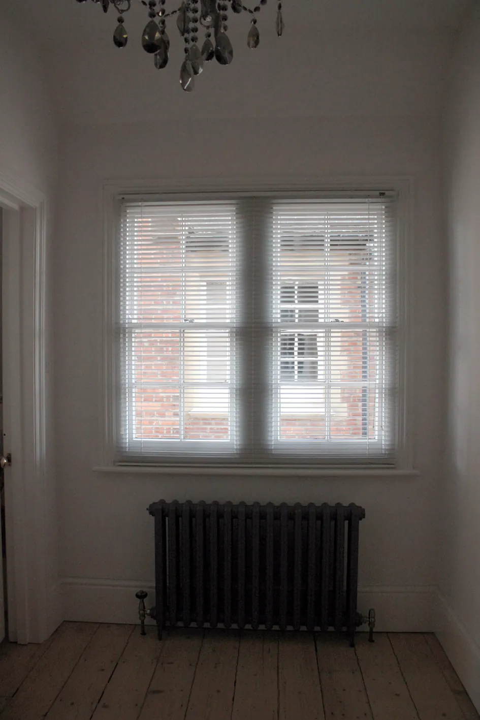Bare timber floorboards and a cast-iron radiator in a Victorian room before floor insulation